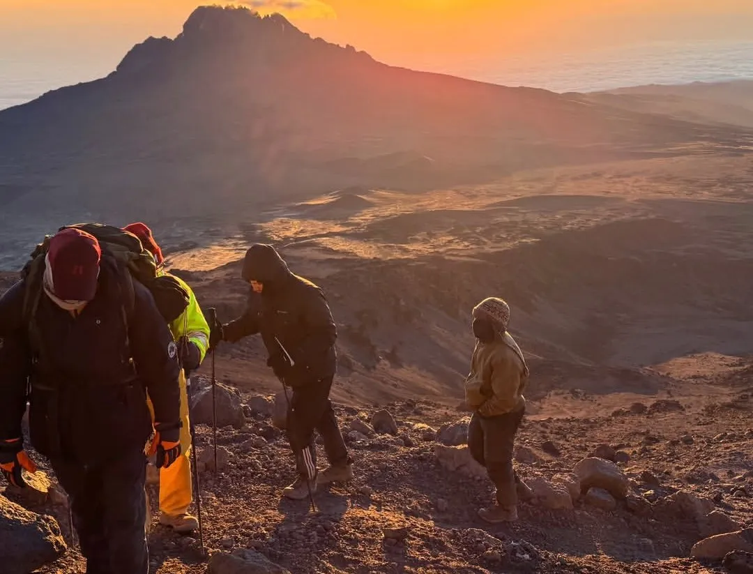 Climbers trekking the Machame Route with Kilimanjaro summit, scenic Shira Plateau, Barranco Wall, mountain tents, and alpine scenery